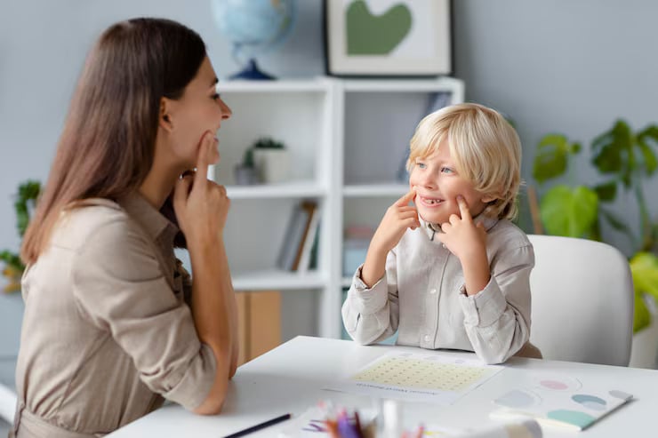 A therapist and a young child practicing facial expressions together during a session